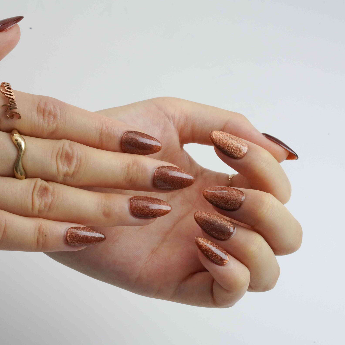 Angled view of Brown Cat Eyes short almond press-on nails showing the reflective brown finish