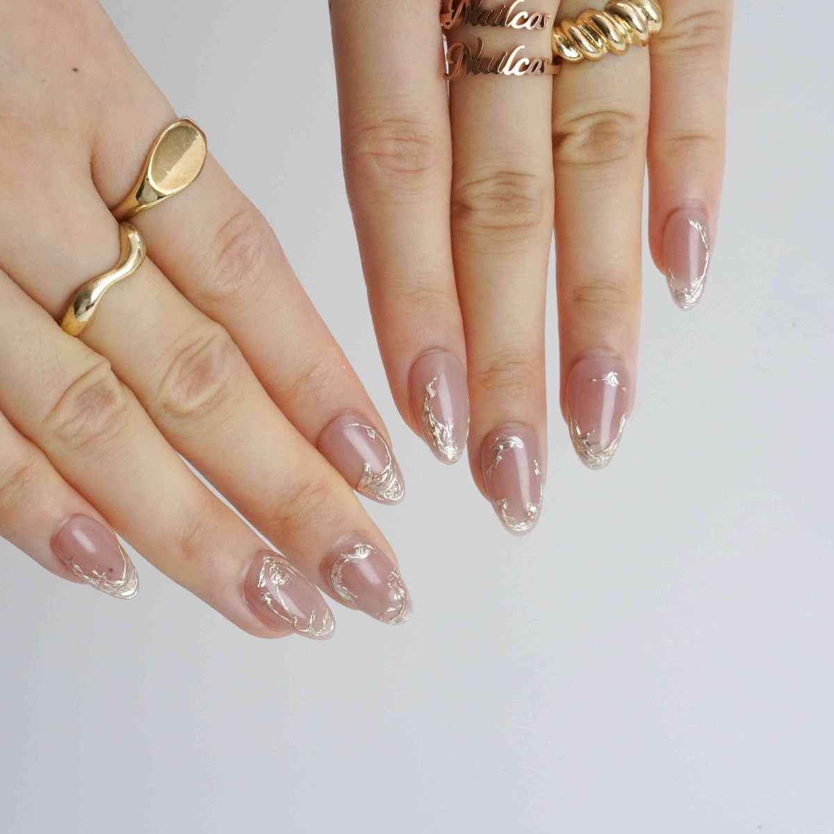 Mocha Swirl nude short almond press-on nails with metallic swirl accents, shown on hands