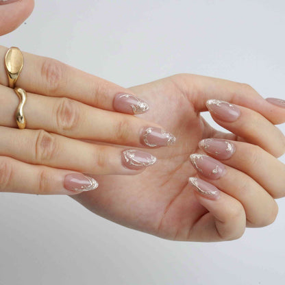 Mocha Swirl nude almond press-on nails with metallic swirl edges, close-up of both hands